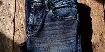 Folded 100% cotton denim jeans on wood, showcasing classic texture and durability.